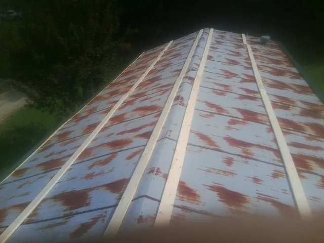 Rusted metal roof panels with new wood purlins before replacement — Storm Damage Roof Repair in Guernsey by Roofing Brothers