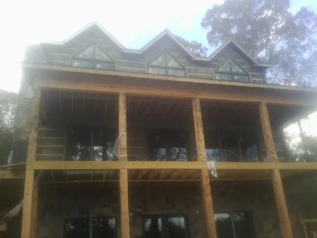 Dormers and porch framing on a large log home under construction — Roof Coating work by our crew in Guernsey