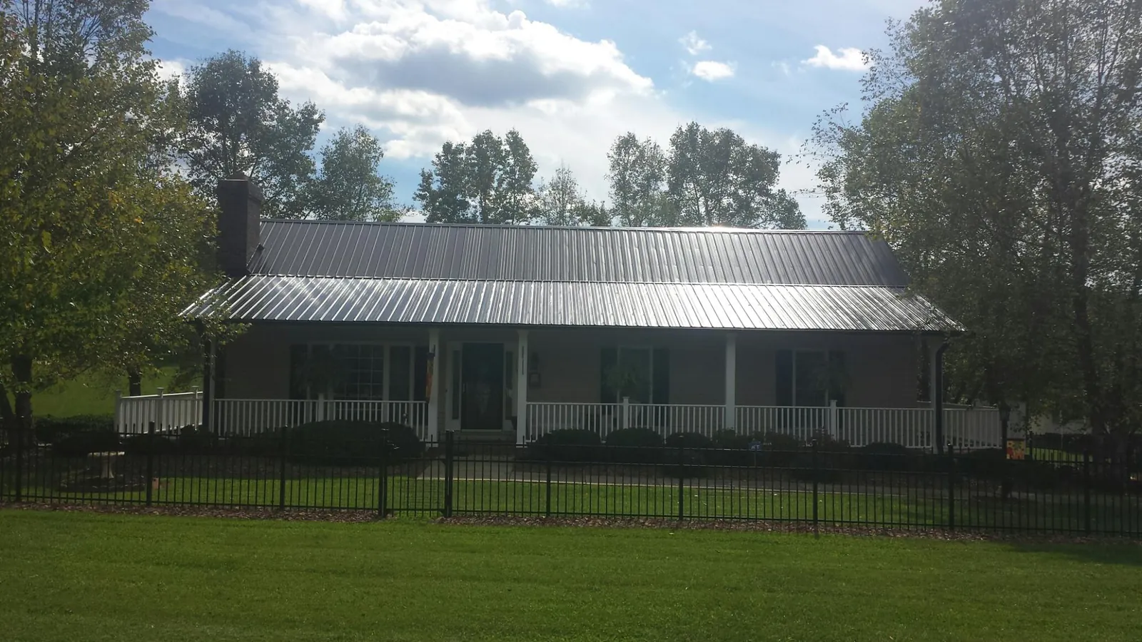 Gray metal roof on a brick ranch with a full width front porch — Gutter Guard Installation work by our crew in Guernsey