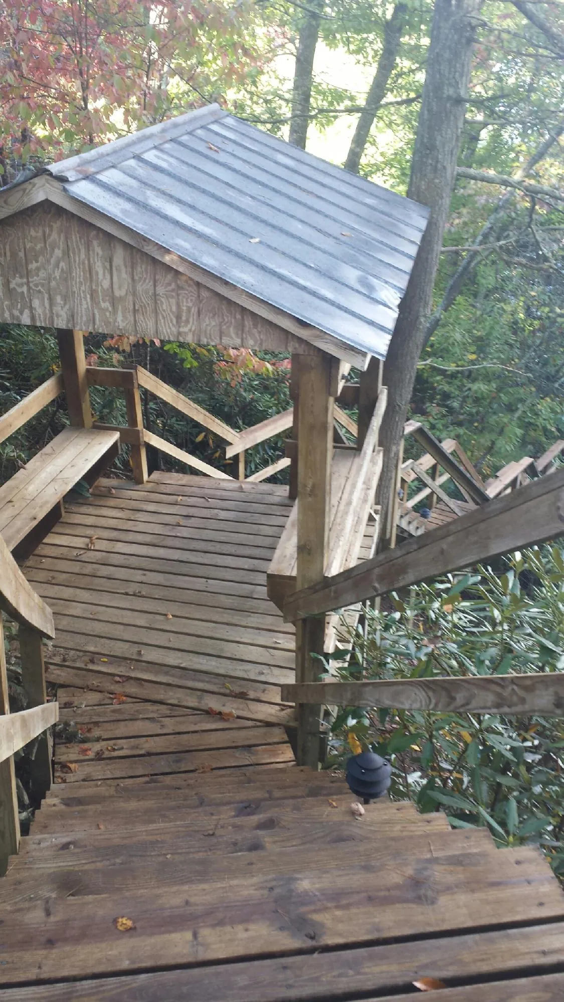 Metal roofed shelter over wooden steps on a wooded walkway — Skylight Repair & Installation work by our crew in Guernsey