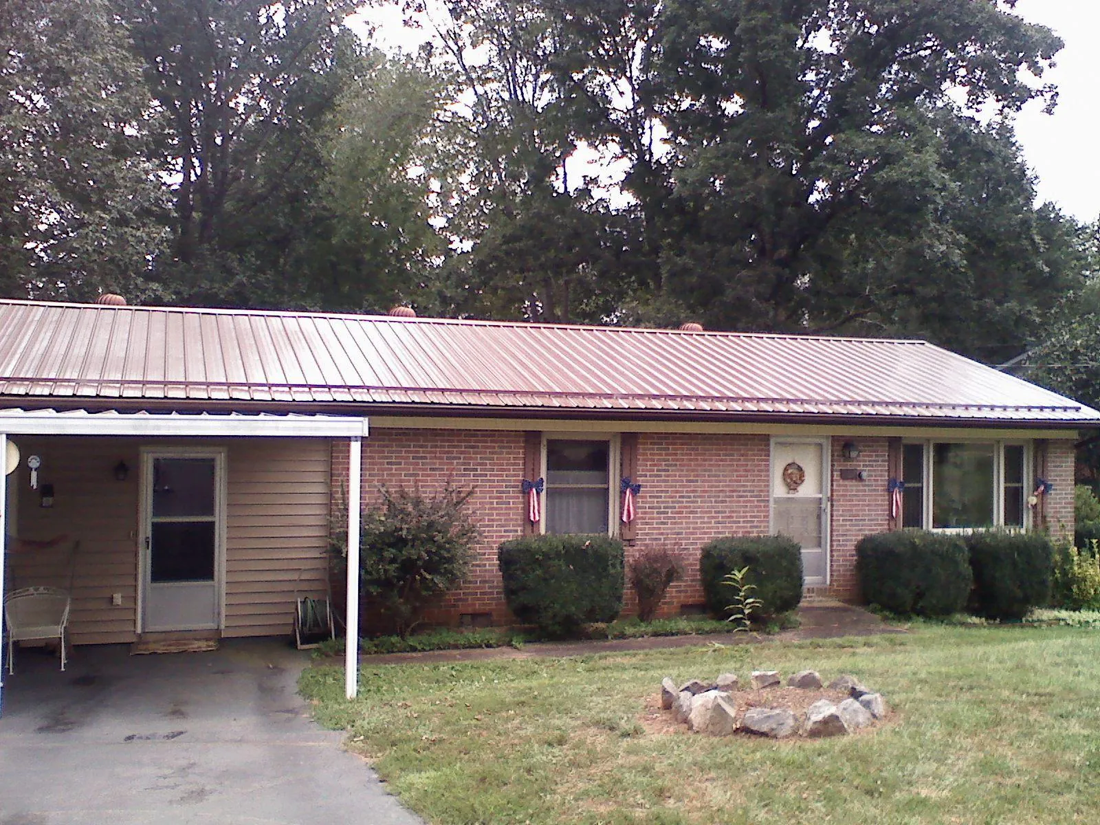 Bronze metal roof and carport on a brick ranch home — Roof Repair work by our crew in Guernsey